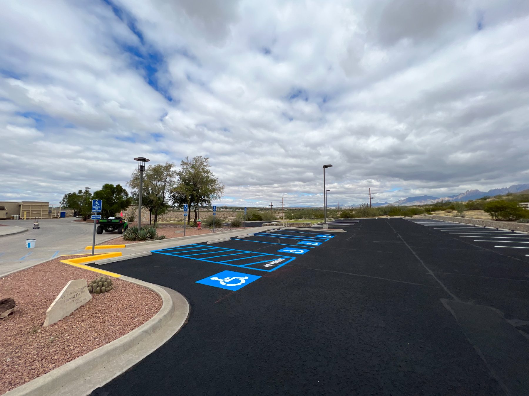 Freshly sealcoated parking lot with new blue accessible striping in Las Cruces, Organ Mountains in the distance